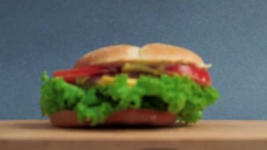 Salatalı, domatesli ve peynirli büyük bir sandviç yukarıdan masaya düşer..