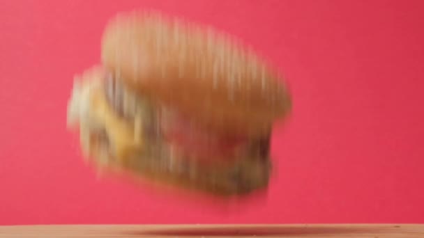 Um grande hambúrguer suculento cai de cima. Comida voadora. Comida rápida de alta caloria. — Vídeo de Stock