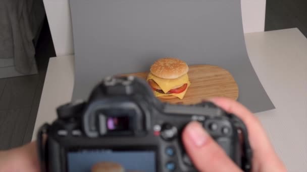 De hand houdt een camera vast en neemt een hamburger. Man blogger, hobby fotografie. — Stockvideo