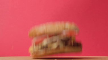 Hızlı yüksek kalorili yiyecekler. Yukarıdan büyük sulu bir hamburger düşüyor. Uçan yemek..
