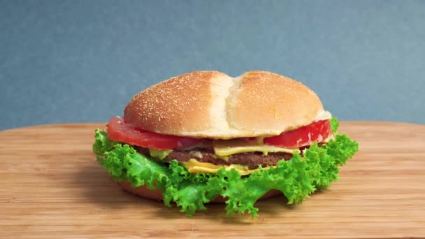 På bordet finns en stor smörgås med sallad, tomat och ost. — Stockvideo