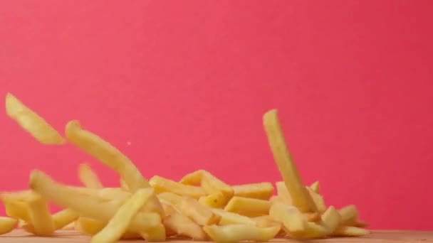 Papas fritas volando en el aire sobre un fondo rosa. Las papas fritas y las hamburguesas están cayendo. — Vídeos de Stock