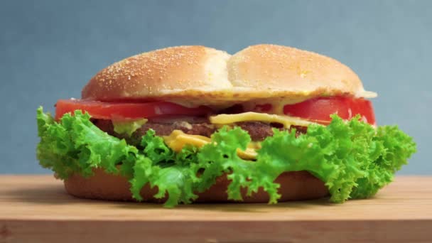 Masanın üzerinde marul, domates ve peynirli büyük bir sandviç var. Mavi arkaplan. — Stok video