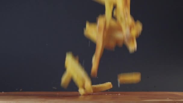 Papas fritas y un sándwich caen sobre la mesa. Concepto de comida rápida. Movimiento lento. — Vídeos de Stock