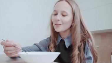 Mutlu kız kahvaltısını mutfakta mısır gevreğiyle yapar. Sabah rutini.