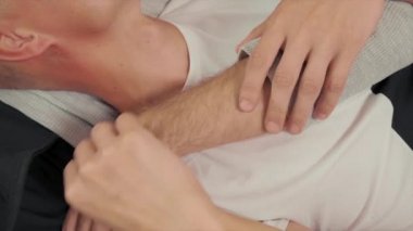 Bir çift eşcinsel adam kanepede yatıyor, bir adam diğer elini okşuyor..