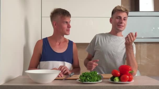 Deux beaux gars dans la cuisine préparent le petit déjeuner, salade. — Video