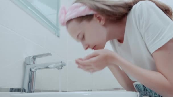 한 아름다운 소녀가 아침에 물로 얼굴을 닦고 있다. — 비디오