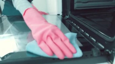 Kız fırının içindeki mutfak kapısını bir bez parçasıyla siliyor. Pembe eldivenli kız..