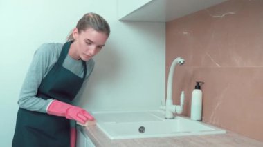 Eldivenli güzel bir kız lavaboyu süngerle yıkıyor..