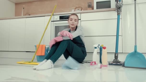 Zmęczona młoda piękna kobieta siedzi na podłodze w kuchni. — Wideo stockowe