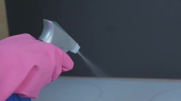 Handen in latex roze handschoenen breng een spray van schoner op het fornuis. — Stockvideo