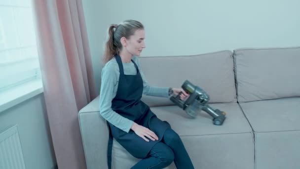 A woman removes wool from the sofa. Large modern washing vacuum cleaner. — Stock Video