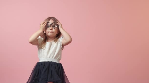 Linda niña en gafas grandes para la visión. Hermoso traje festivo brillante. — Vídeos de Stock