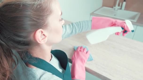 若い女の子のプロのクリーナーは、テーブルの上に洗浄剤を噴霧. — ストック動画