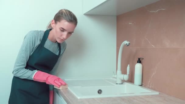 A beautiful girl in gloves washes the washbasin with a sponge, cleaning agent. — Stock Video