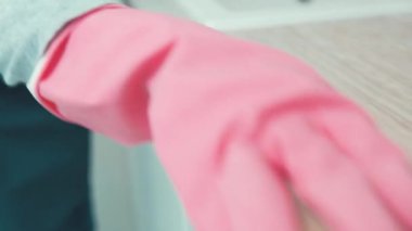 Eldivenli güzel bir kız lavabonun yanındaki komodini yıkıyor..