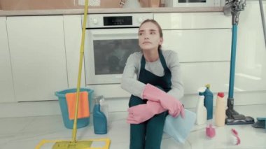 Memnun genç ve güzel bir kadın mutfakta yerde oturuyor..