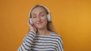 Genç ve güzel bir kadın kulaklıkla müzik dinliyor. Müziğin tadını çıkar.