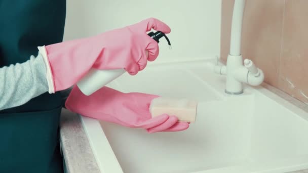 Τα κορίτσια χέρια σε γάντια λατέξ εφαρμόστε ένα καθαριστικό μέσο στο σφουγγάρι καθαρισμού. — Αρχείο Βίντεο