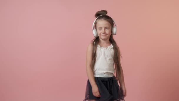 Gyönyörű lány fülhallgatóval hallgat zenét. Gyönyörű fényes ünnepi ruha — Stock videók