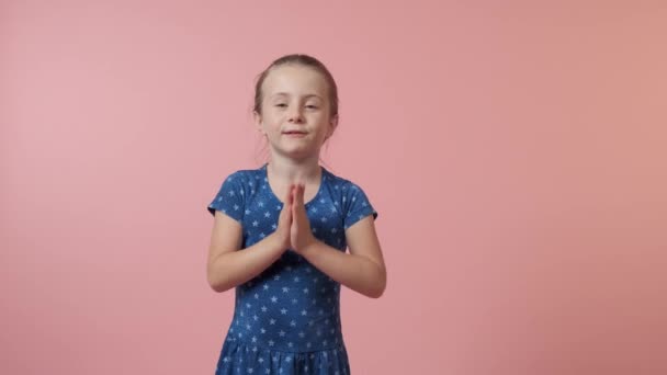 Egy gyönyörű, aranyos lány összekulcsolta a kezét és kért valamit.. — Stock videók