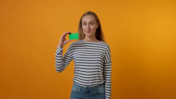 Egy gyönyörű fiatal nő üres zöldkártyát tart a kezében.. — Stock videók