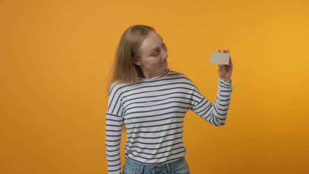 Πορτρέτο του κοριτσιού κρατώντας κάρτα στο χέρι απομονωμένη διαφήμιση, κίτρινο φόντο. — Αρχείο Βίντεο