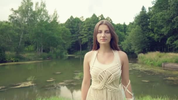 Una hermosa joven mira a la cámara y camina hacia adelante. Mirada llamativa — Vídeos de Stock