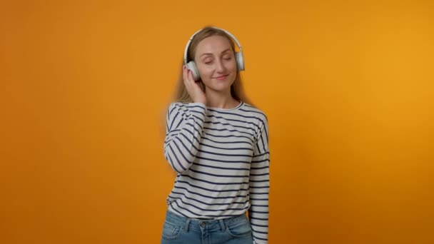Νεαρή όμορφη γυναίκα ακούει μουσική με μεγάλα λευκά ακουστικά. Απολαύστε τη μουσική. — Αρχείο Βίντεο