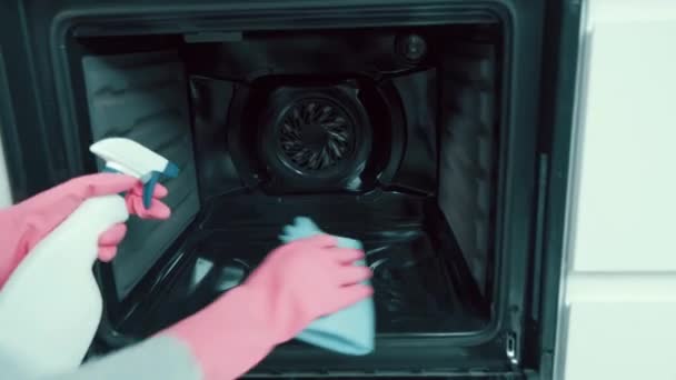 Dziewczyna sprząta, myje się w piekarniku w kuchni detergentem, spryskuje. — Wideo stockowe
