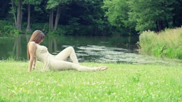 Uma jovem a dançar no prado. Contra o fundo do lago e da floresta — Vídeo de Stock