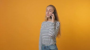 Güzel genç bir kadın cep telefonuyla konuşuyor. Serbest bir iş. Sarı arkaplan
