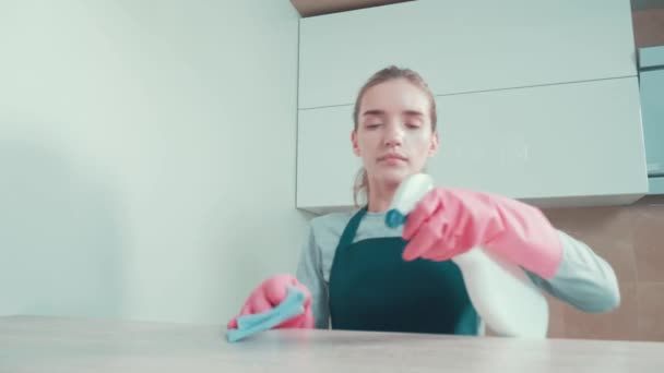 Une jeune fille nettoyante applique un agent nettoyant sur la surface de la table avec un spray. — Video