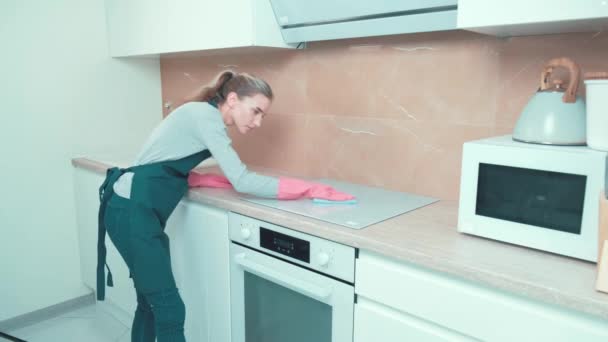 La chica hace la limpieza diligentemente en la cocina, lava la estufa. — Vídeos de Stock