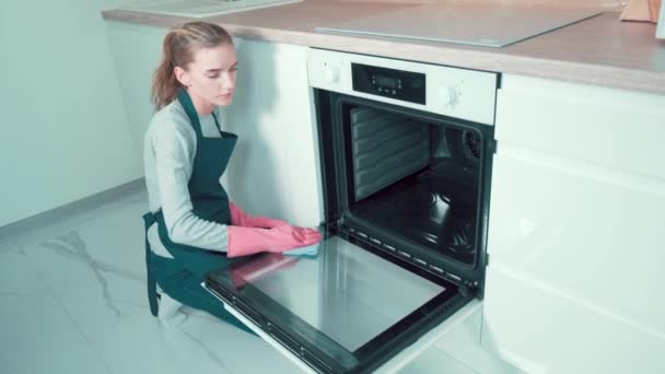 那姑娘的职业清洁工用一块破烤箱擦了擦里面的门. — 图库视频影像