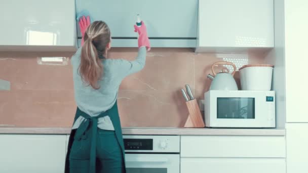 Vacker ung blond flicka torkar köket huva med rengöringsmedel. — Stockvideo
