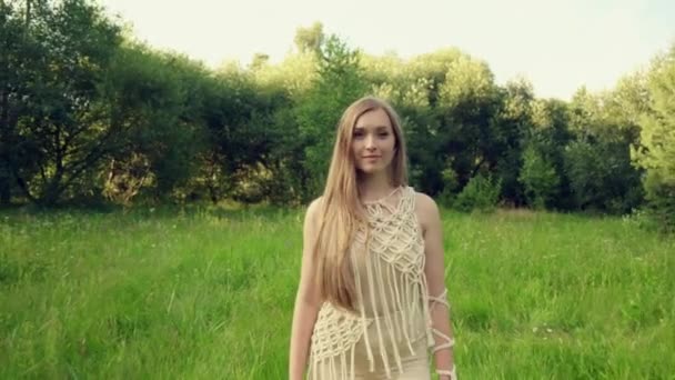 Uma bela jovem está andando em um campo com grama verde brilhante. Vídeo 4K. — Vídeo de Stock