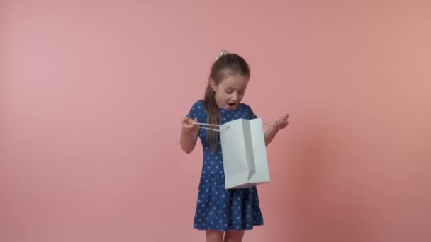Маленькая девочка показывает свой подарок и смотрит в камеру. — стоковое видео