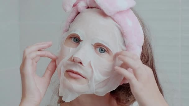 O fată frumoasă cu o mască de țesătură pe față, un bandaj moale pe cap . — Videoclip de stoc