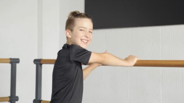 Jonge knappe jongensdanser die naar de camera kijkt. Training op een balletschool. — Stockvideo