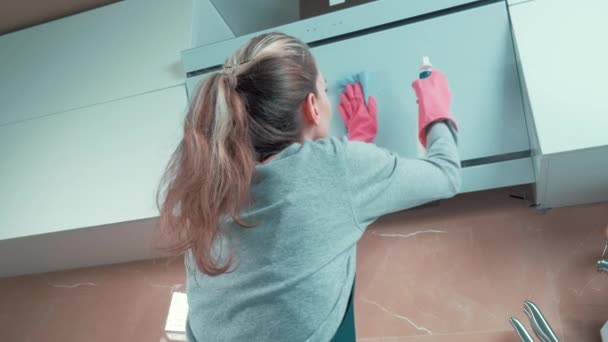 Menina loira bonita limpa o capuz da cozinha com agente de limpeza. — Vídeo de Stock