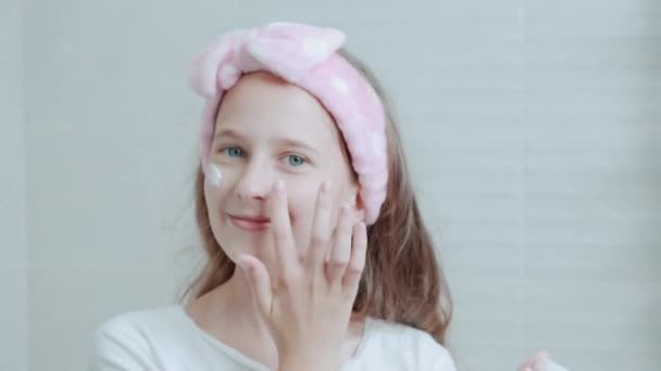 Eine weiße Feuchtigkeitscreme auf ein sauberes, schönes junges Gesicht auftragen. Hautpflege. — Stockvideo