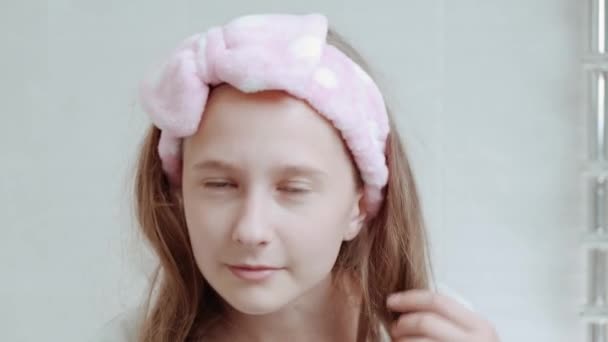 Una giovane bella ragazza con una benda morbida sulla testa si guarda allo specchio. — Video Stock