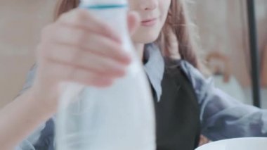 Bir kız mutfakta mısır gevreğiyle kahvaltı yapıyor. Sabah rutini.