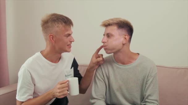 Gay couple communicate while sitting on the couch. They indulge in and laugh. — Stock Video