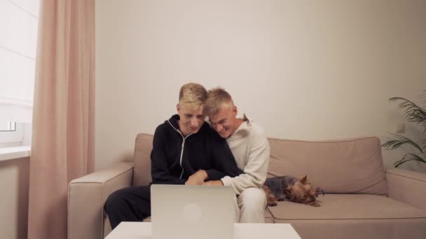 A słodkie gej para są siedzi w domu w ich piżama śmiech. — Wideo stockowe