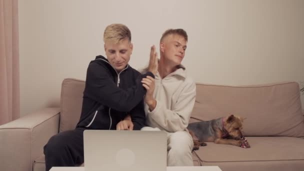 Una coppia gay sono seduti a casa in pigiama, guardando un film insieme. — Video Stock