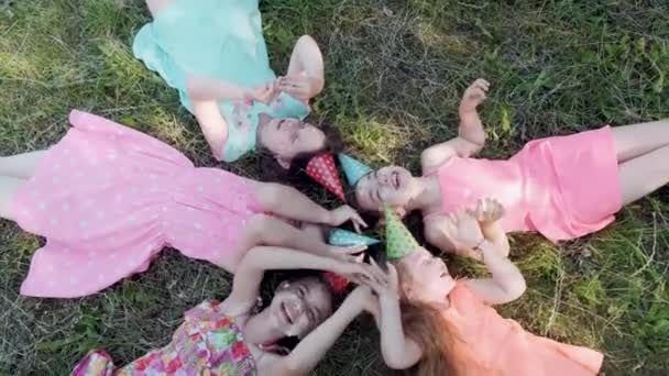 Beautiful cute girls lie on the grass, their face is smeared with whipped cream. — Stock Video