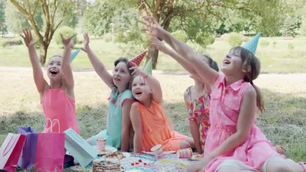 Piękne dziewczyny w sukienkach w parku wyciągają ręce do góry, proszą o deser. — Wideo stockowe